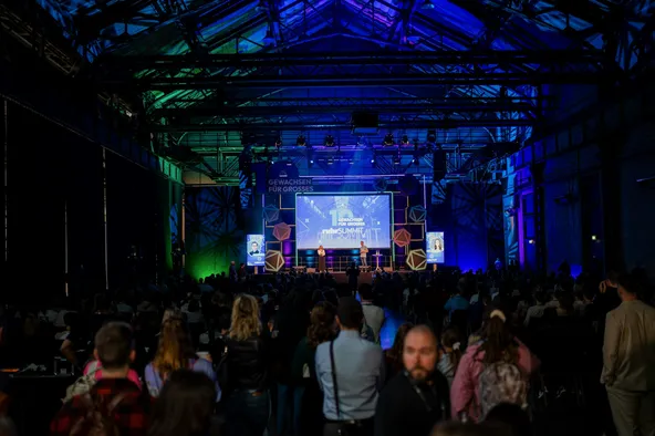 Blick auf die beleuchtete Main Stage des RuhrSummit 2025. Im Vordergrund ist das Publikum zu sehen.
