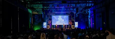 Blick auf die beleuchtete Main Stage des RuhrSummit 2025. Im Vordergrund ist das Publikum zu sehen.